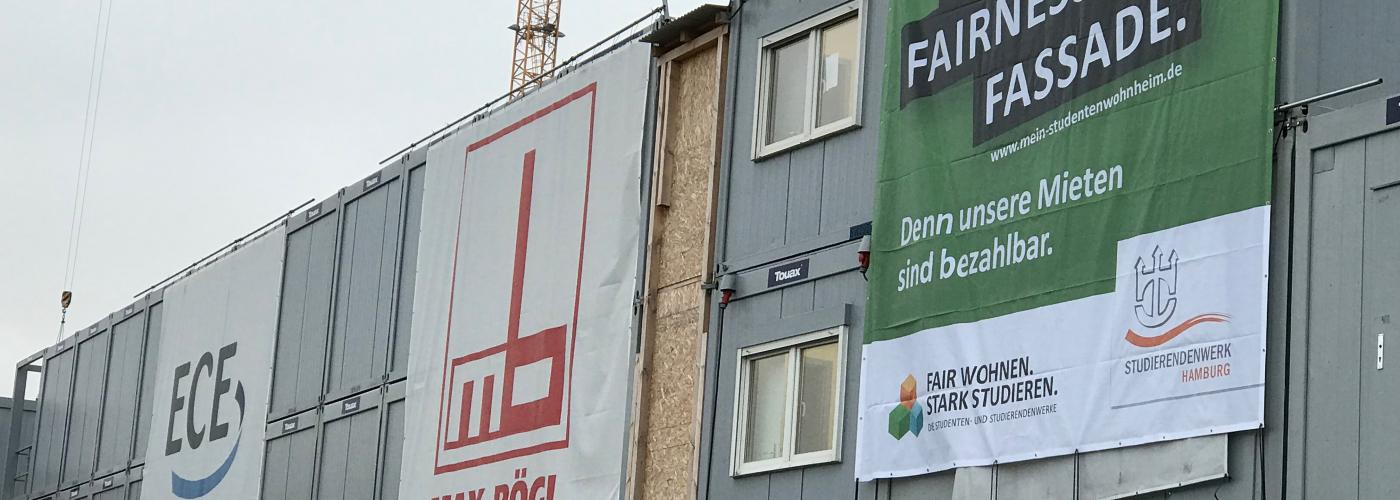 Mehrere Baustellenbanner mit Kränen im Hintergrund